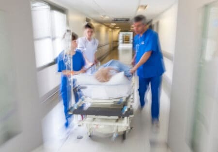 patient being moved on gurney through hospital hallway