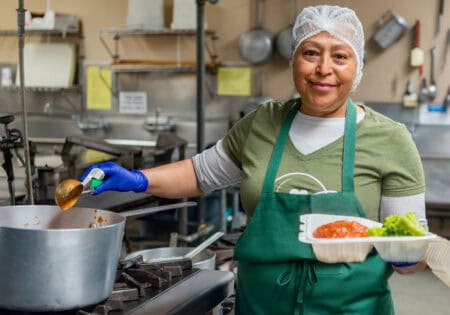 food service worker serving a plate of food